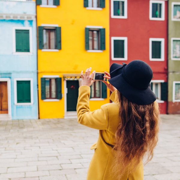 Woman photographing brightly painted house.